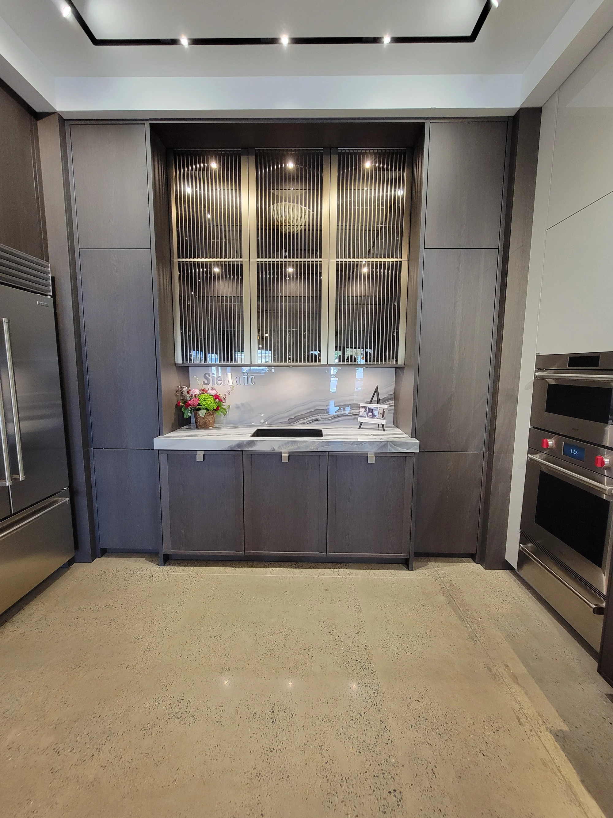 Installed SieMatic display with glazed cabinetry and a stone counter